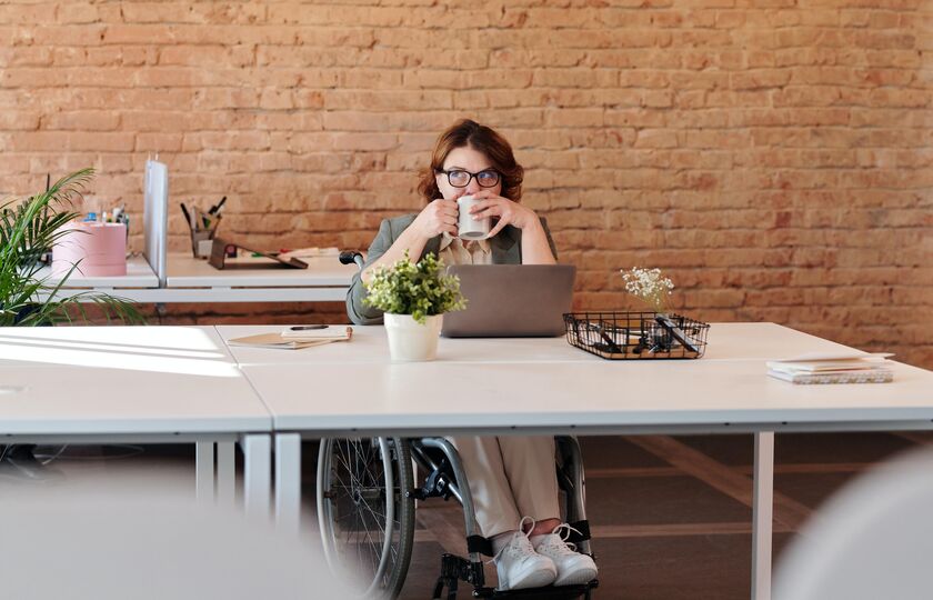 Woman in wheelchair on computer with mug